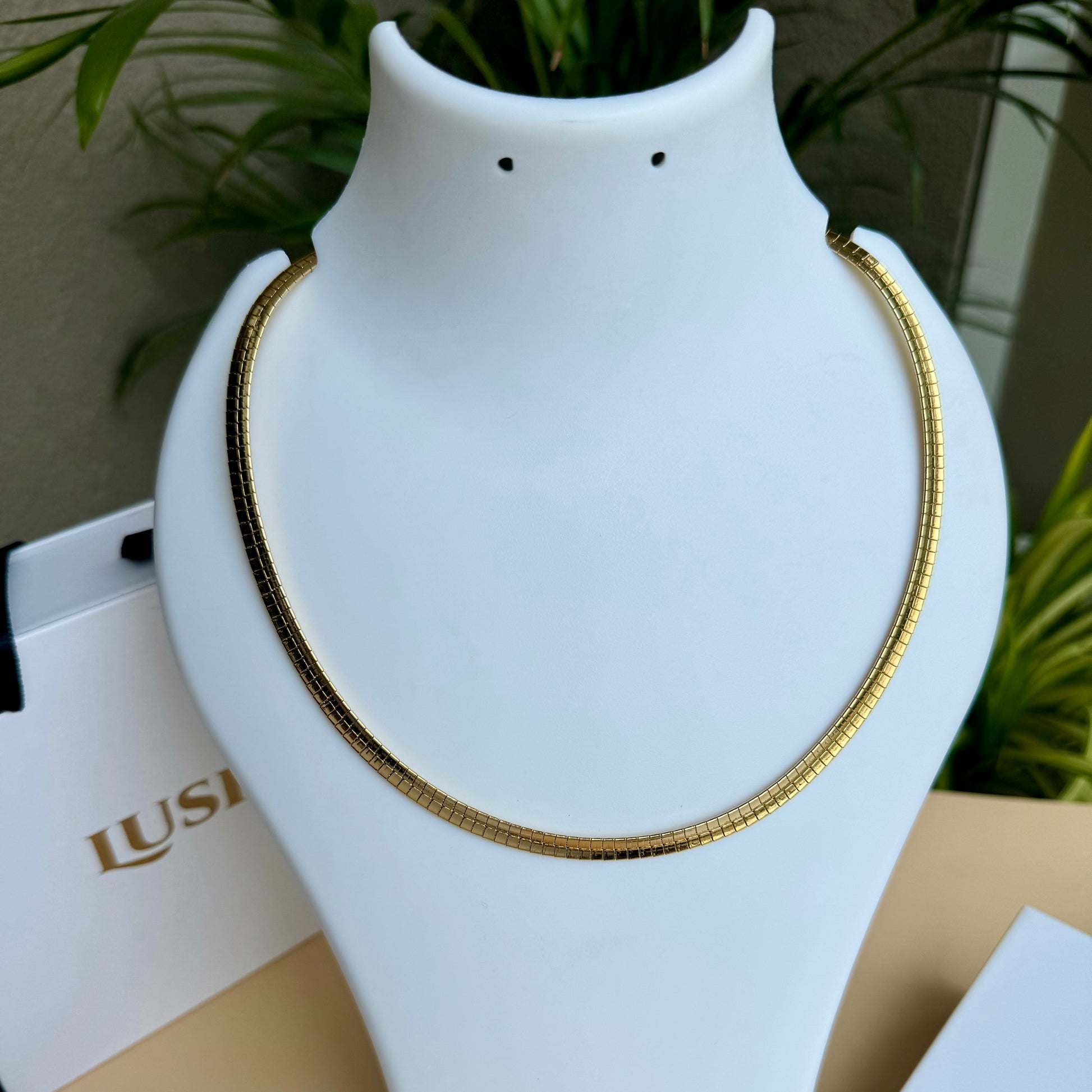 Elegant gold chain necklace displayed on a white bust.