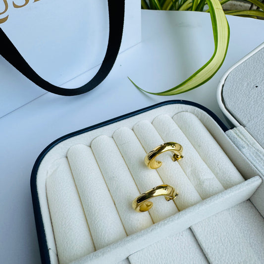 The earrings are circular or semi-circular in shape and appear to be made of a shiny, yellow metal, consistent with the appearance of gold. They are displayed in a jewelry case, suggesting they are a valuable item