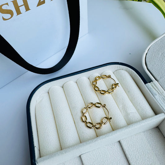 Elegant gold chain-link hoop earrings displayed in a plush, cream-colored jewelry case, exuding sophistication and contemporary charm.