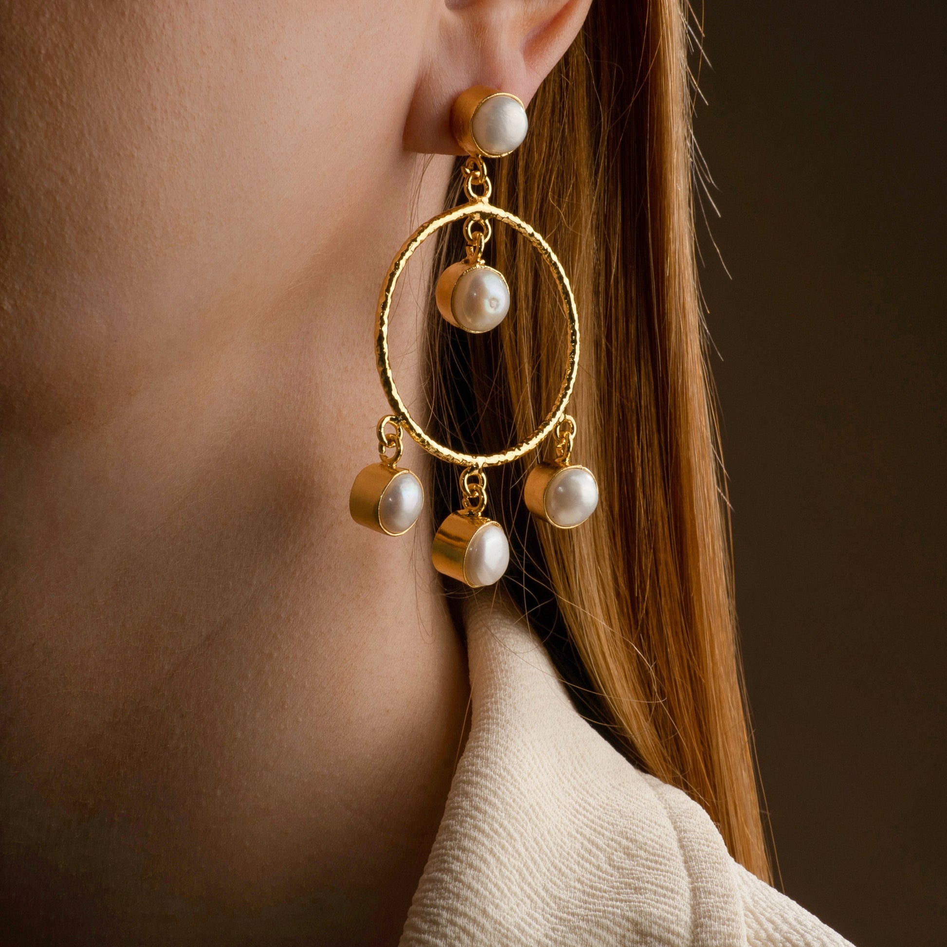 model wearing a gold-plated statement hoop earring adorned with dangling white pearls, showcasing elegant and contemporary jewelry design