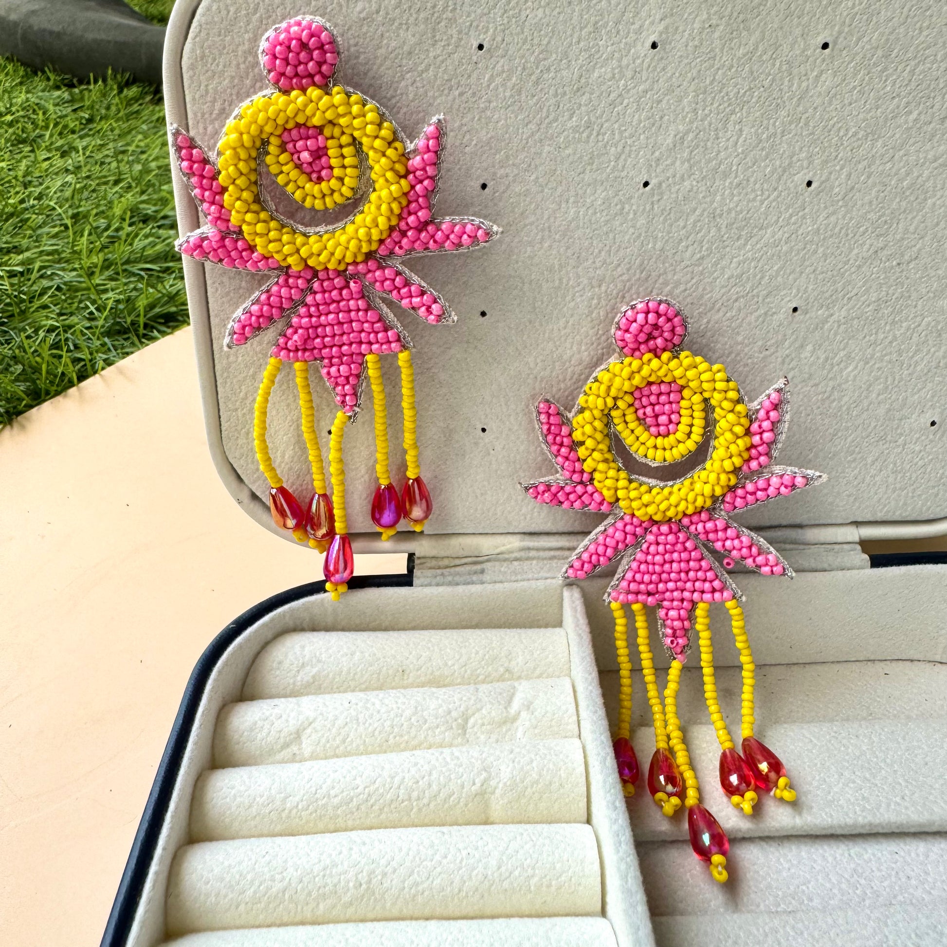 Vibrant pink and yellow beaded statement earrings with playful fringe and red teardrop accents, radiating bold, eclectic energy