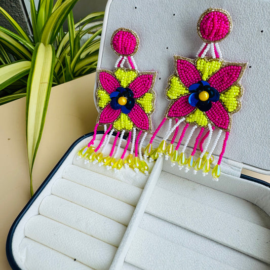 Intricate beaded earrings with a central pink floral design, yellow petal-like shapes, and a beaded fringe.