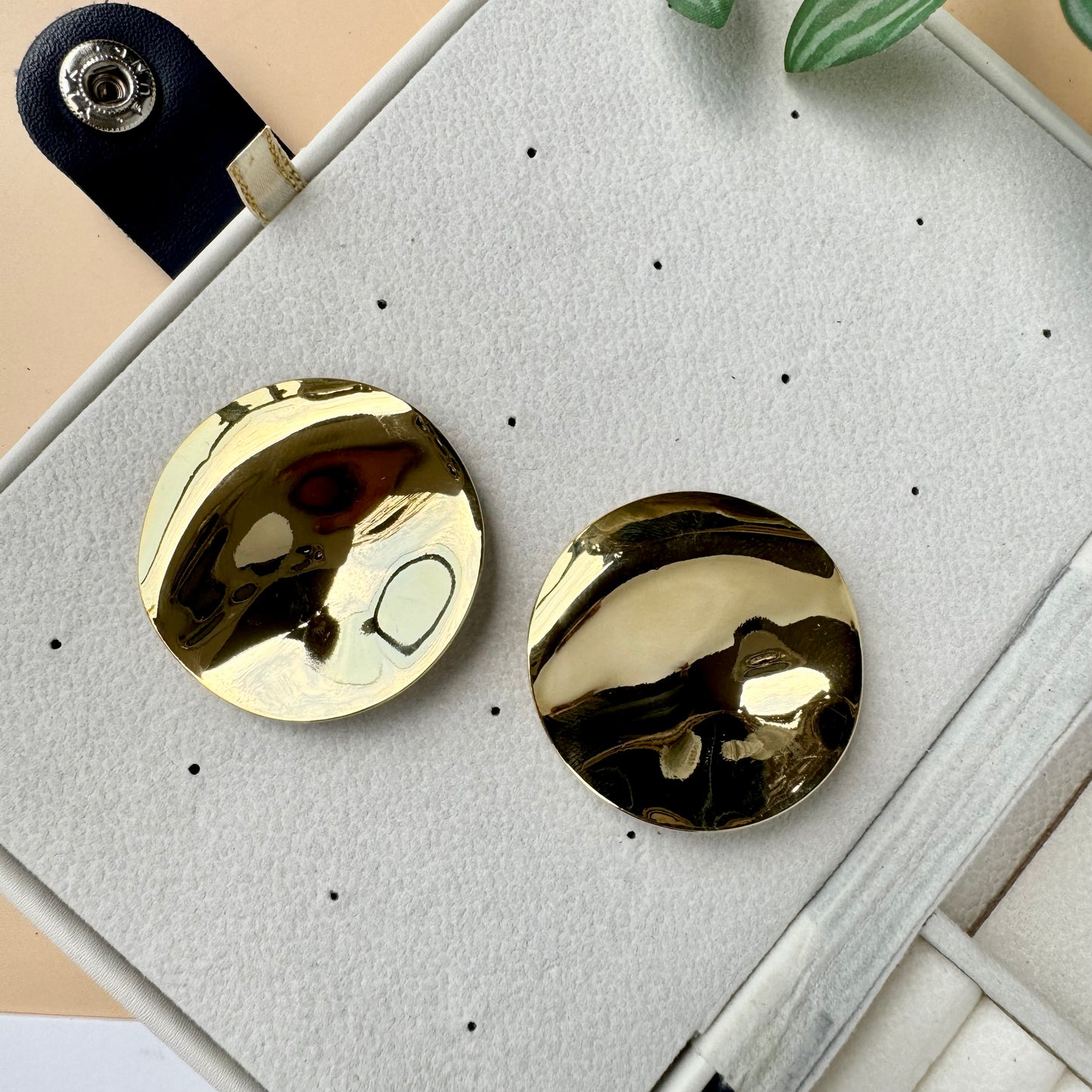 An 18k gold-plated stainless steel mirror finish earrings showcased on a brown velvet pillow. The earring has a solid, tarnish-free appearance.