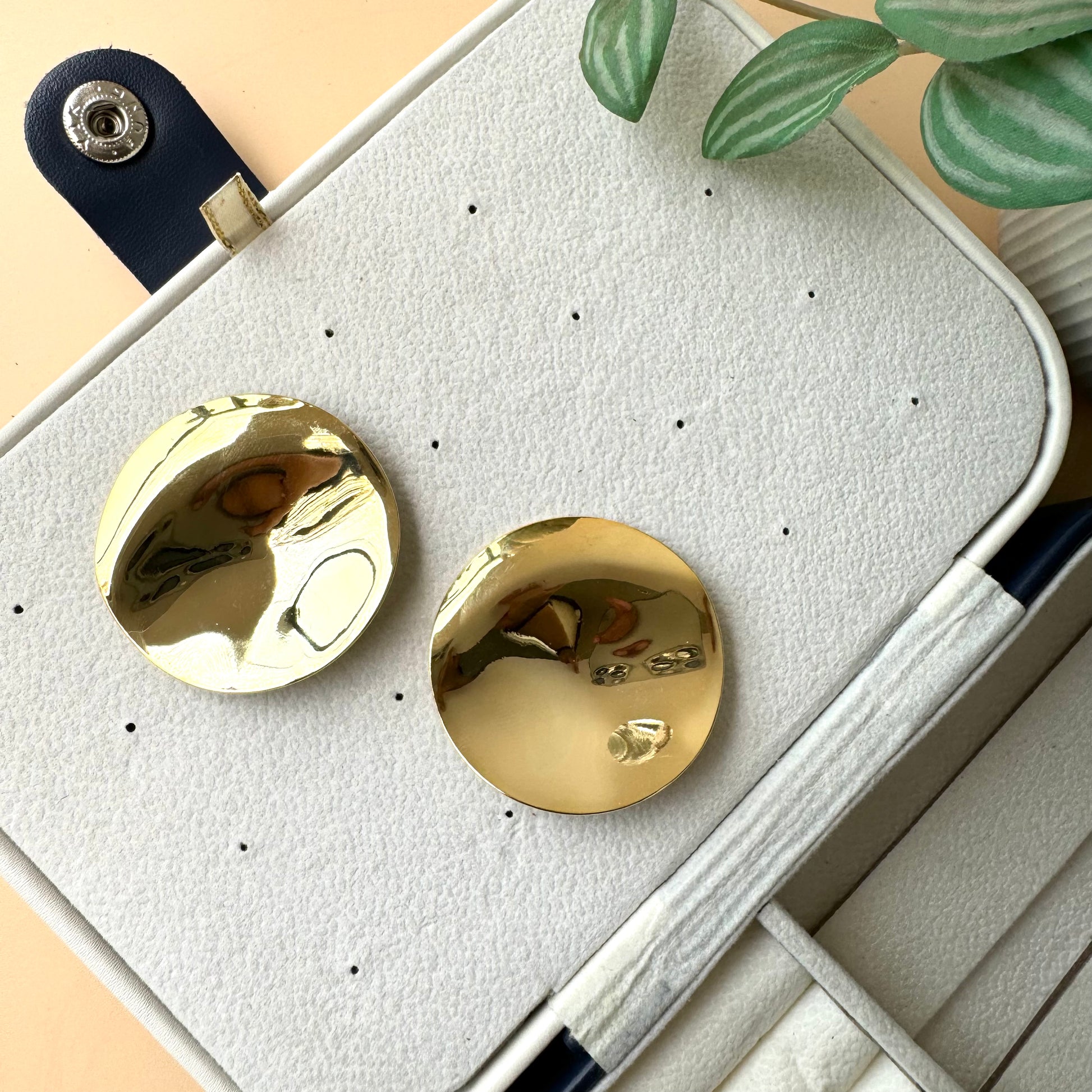An 18k gold-plated stainless steel mirror finish earrings showcased on a brown velvet pillow. The earring has a solid, tarnish-free appearance.