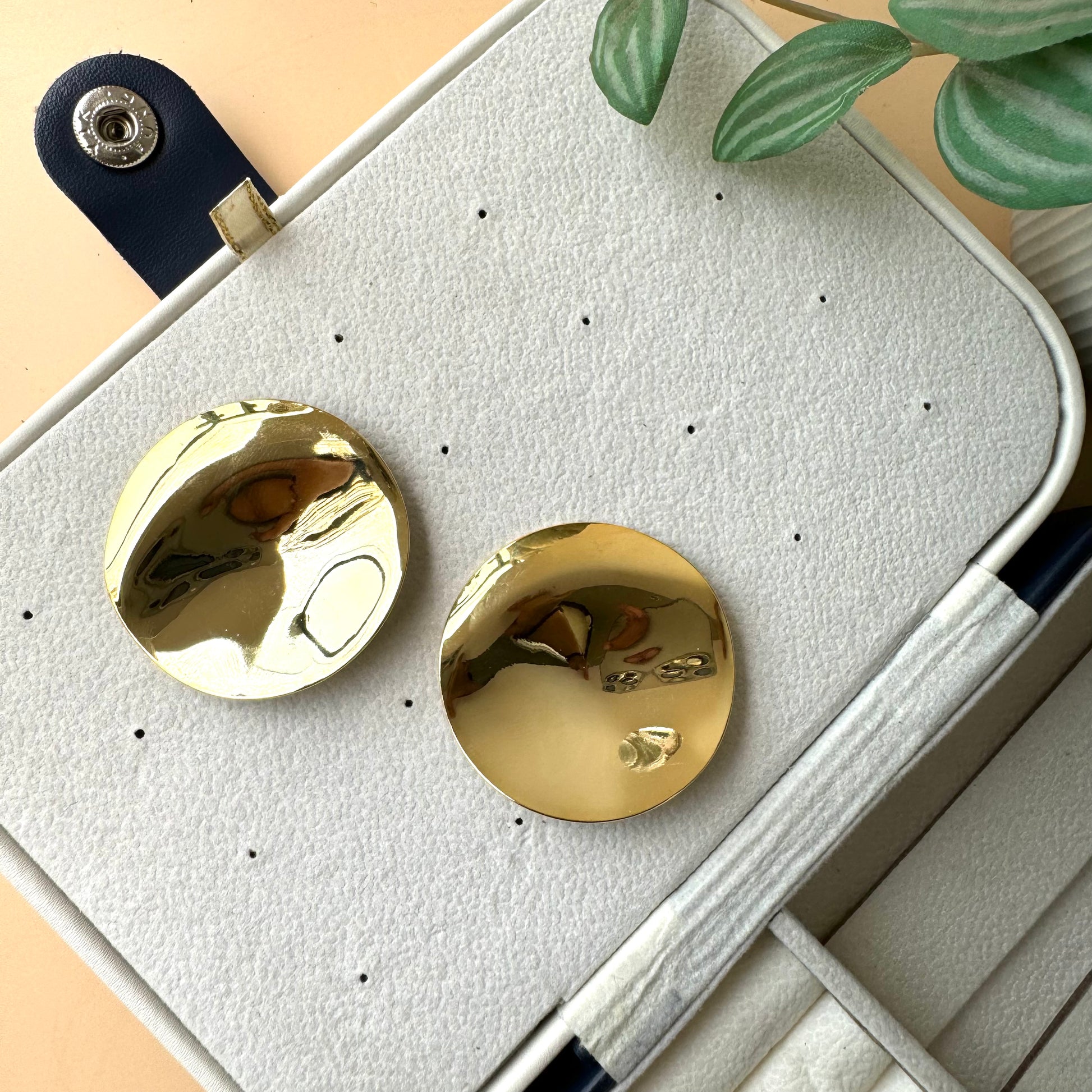 An 18k gold-plated stainless steel mirror finish earrings showcased on a brown velvet pillow. The earring has a solid, tarnish-free appearance.