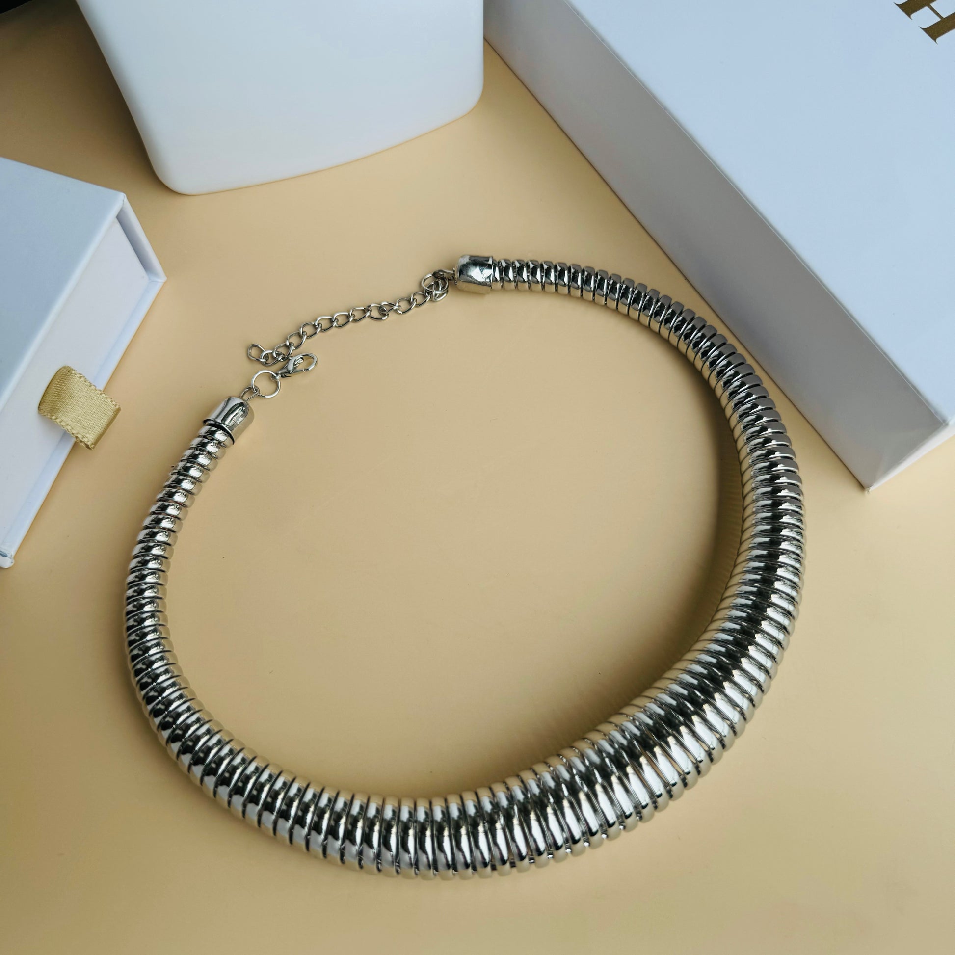 Silver-tone tubular choker necklace on a white display bust