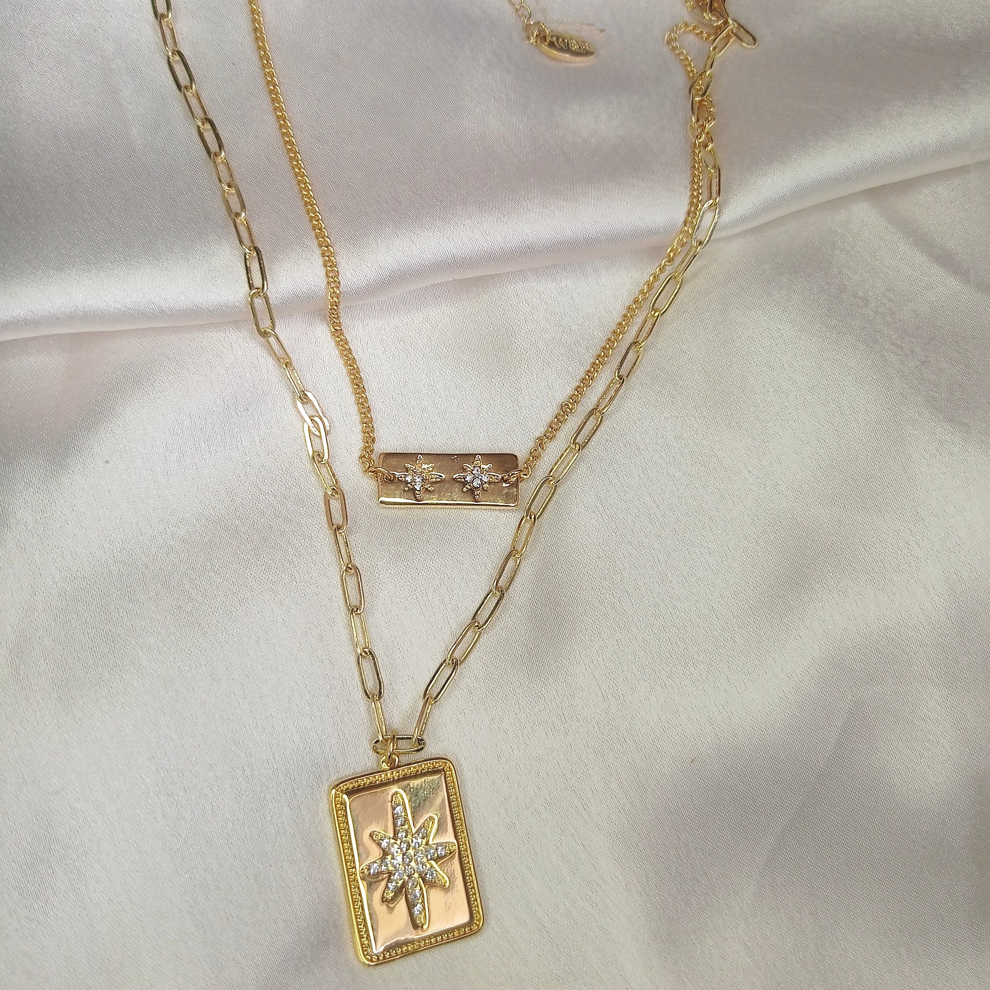 Trendy layered gold necklace with rectangular pendant charms featuring intricate designs, perfect for boho-chic and statement jewelry lovers