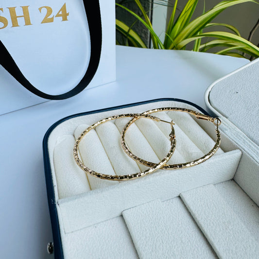 Elegant textured gold hoop earrings displayed in a luxurious jewelry case, showcasing their classic yet modern appea
