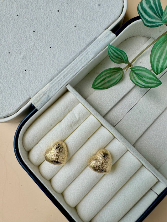 An 18k gold-plated stainless steel earrings designed to be tarnish-free and waterproof, displayed on a small brown cushion. 