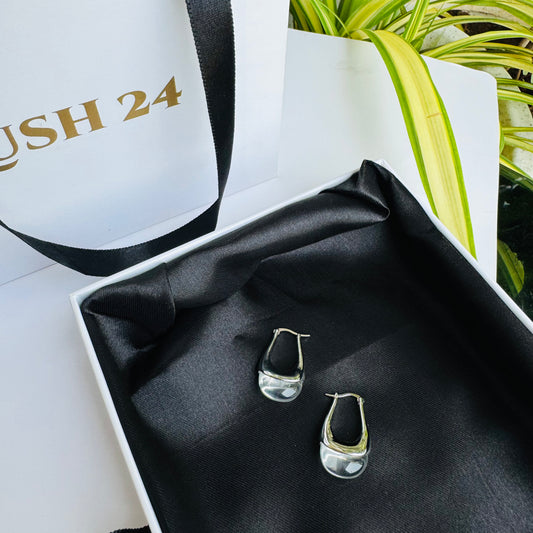 Sleek and modern silver earrings with a fluid, organic design, elegantly displayed on black satin in a premium gift box