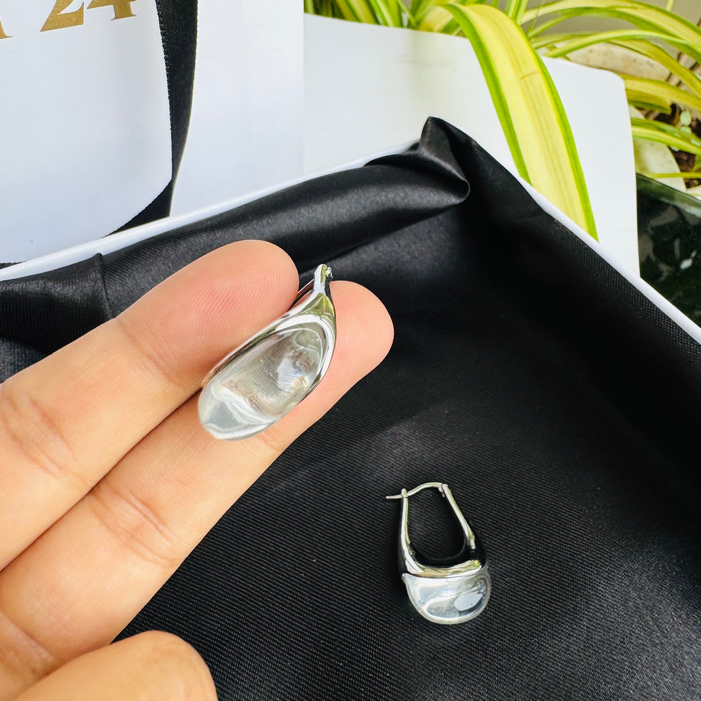 Sleek and modern silver earrings with a fluid, organic design, elegantly displayed on black satin in a premium gift box