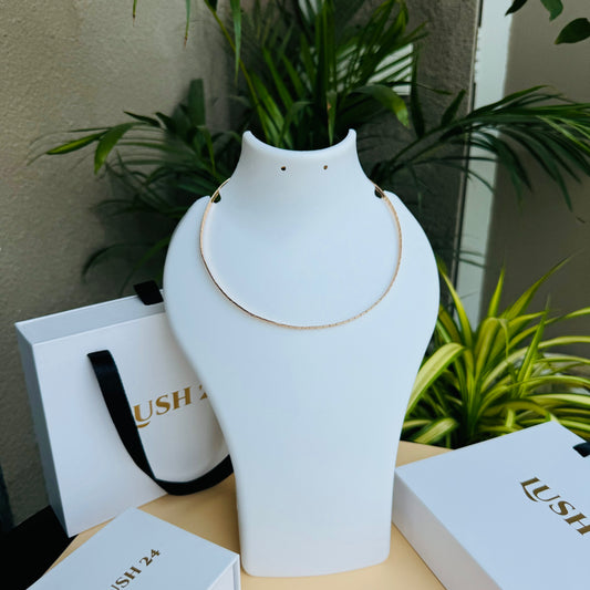 Close-up of a ultra luxe thin necklace with delicate chains in  gold finishes, connected by a single clasp. It is nestled in a Lush 24 branded gift box