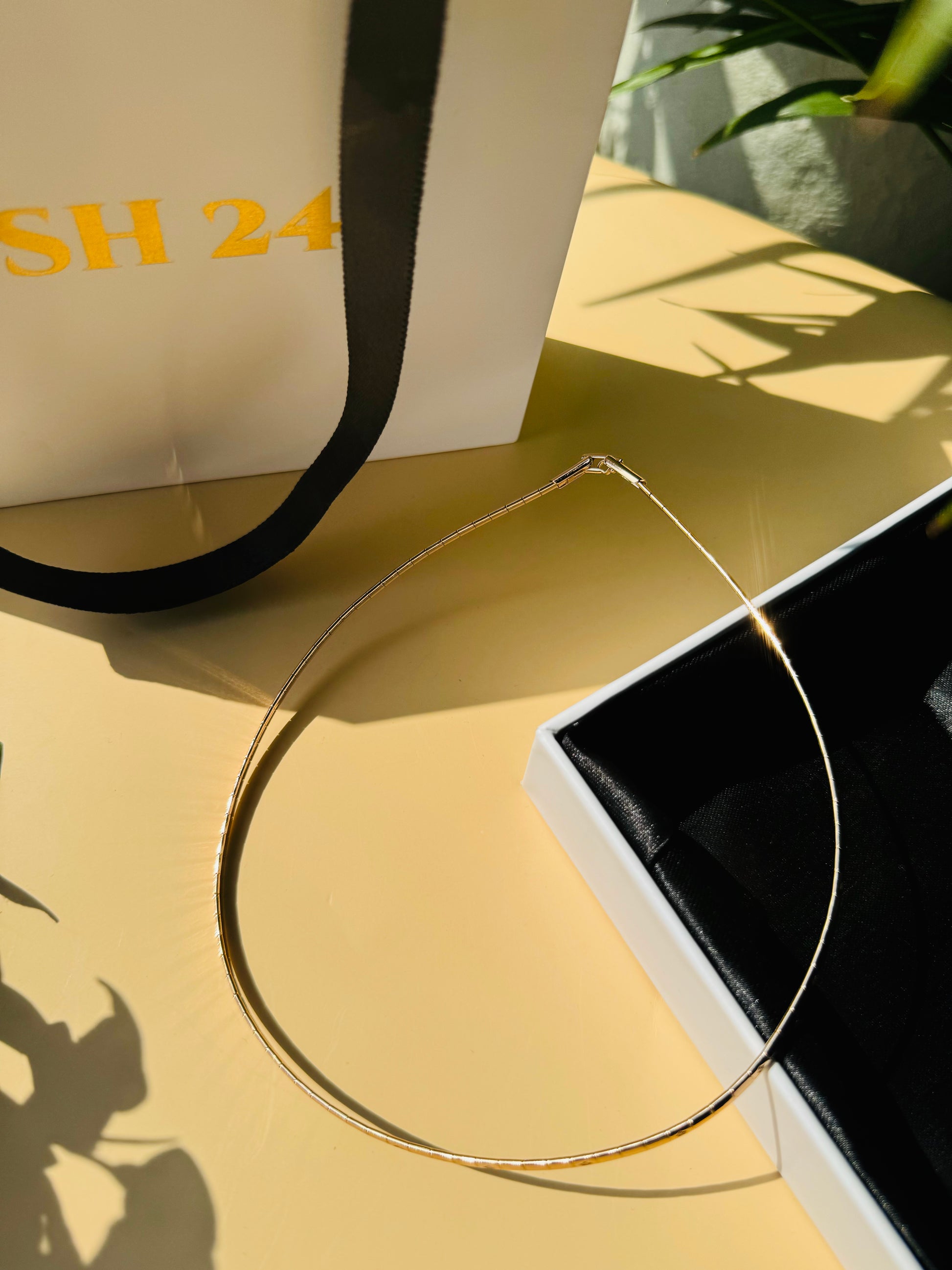 Close-up of a ultra luxe thin necklace with delicate chains in  gold finishes, connected by a single clasp. It is nestled in a Lush 24 branded gift box