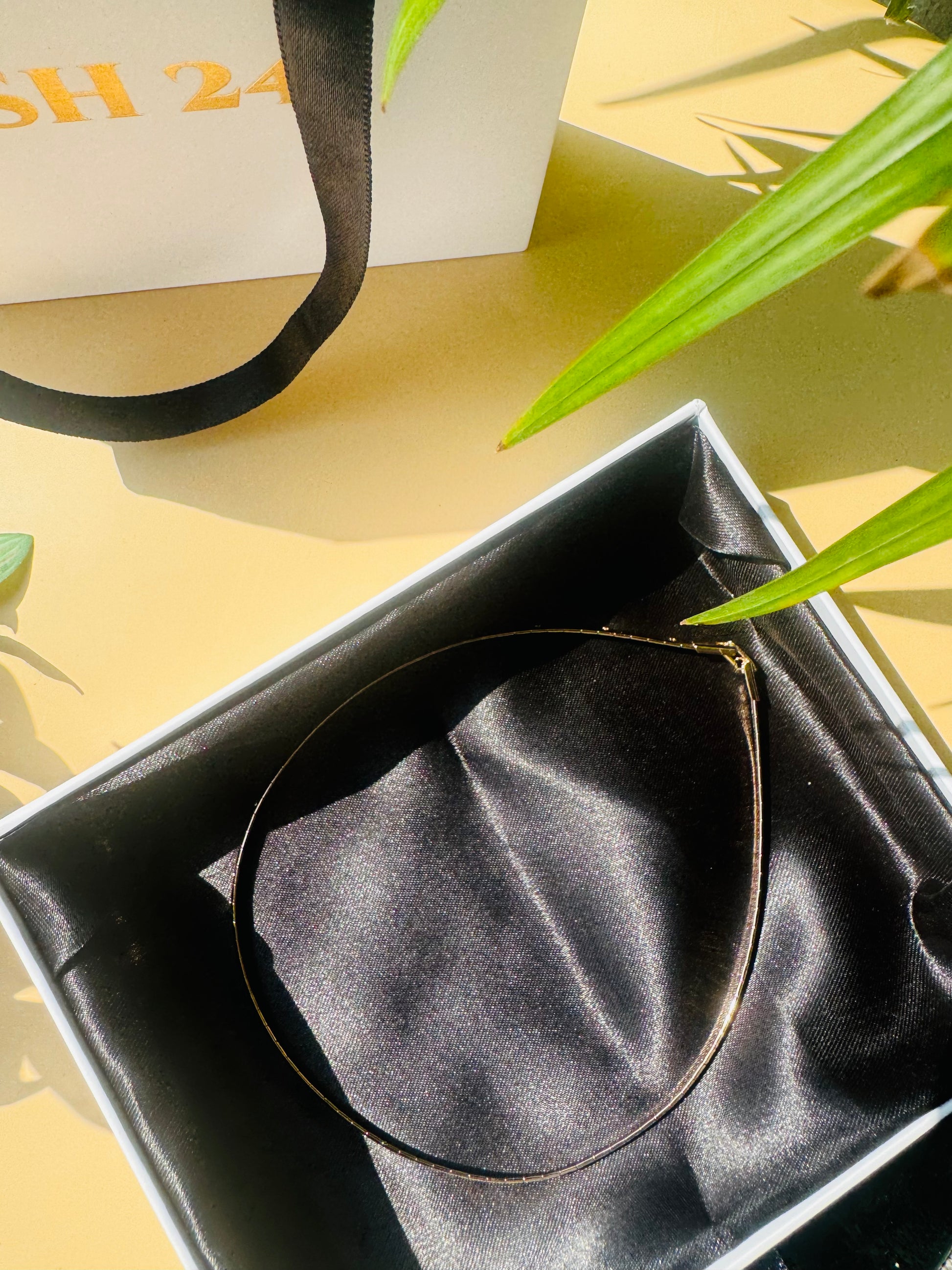 Close-up of a ultra luxe thin necklace with delicate chains in  gold finishes, connected by a single clasp. It is nestled in a Lush 24 branded gift box